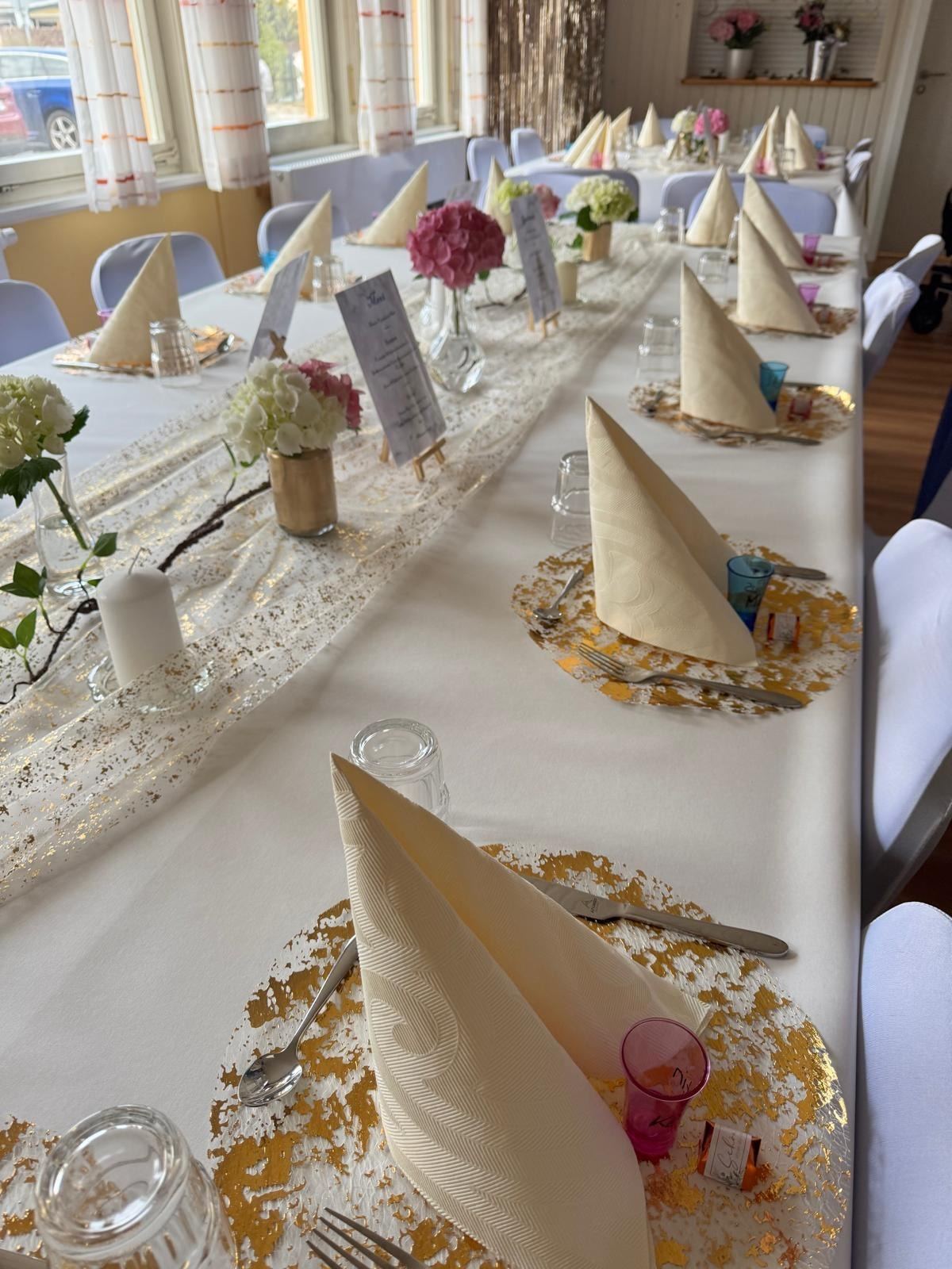 Festlich gedeckte Tafel mit goldenen Platztellern und Blumen
